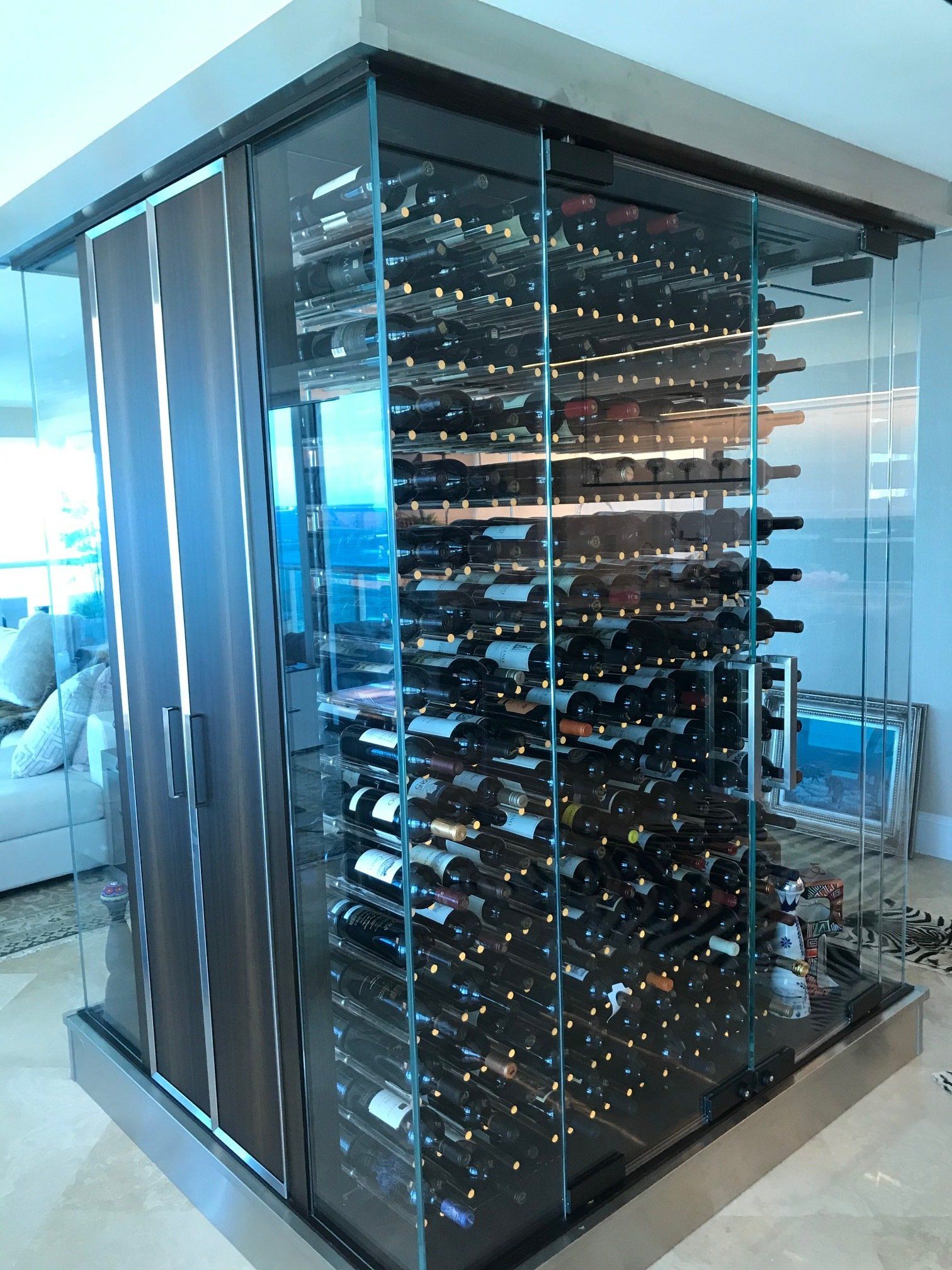 A wine cellar filled with lots of bottles of wine in a living room.