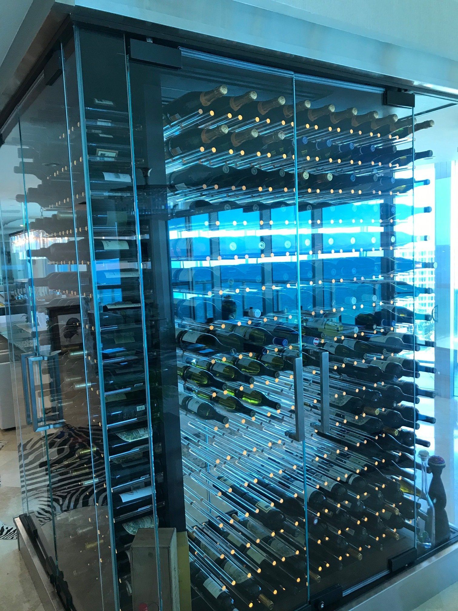 A large glass wine cellar filled with lots of bottles of wine.