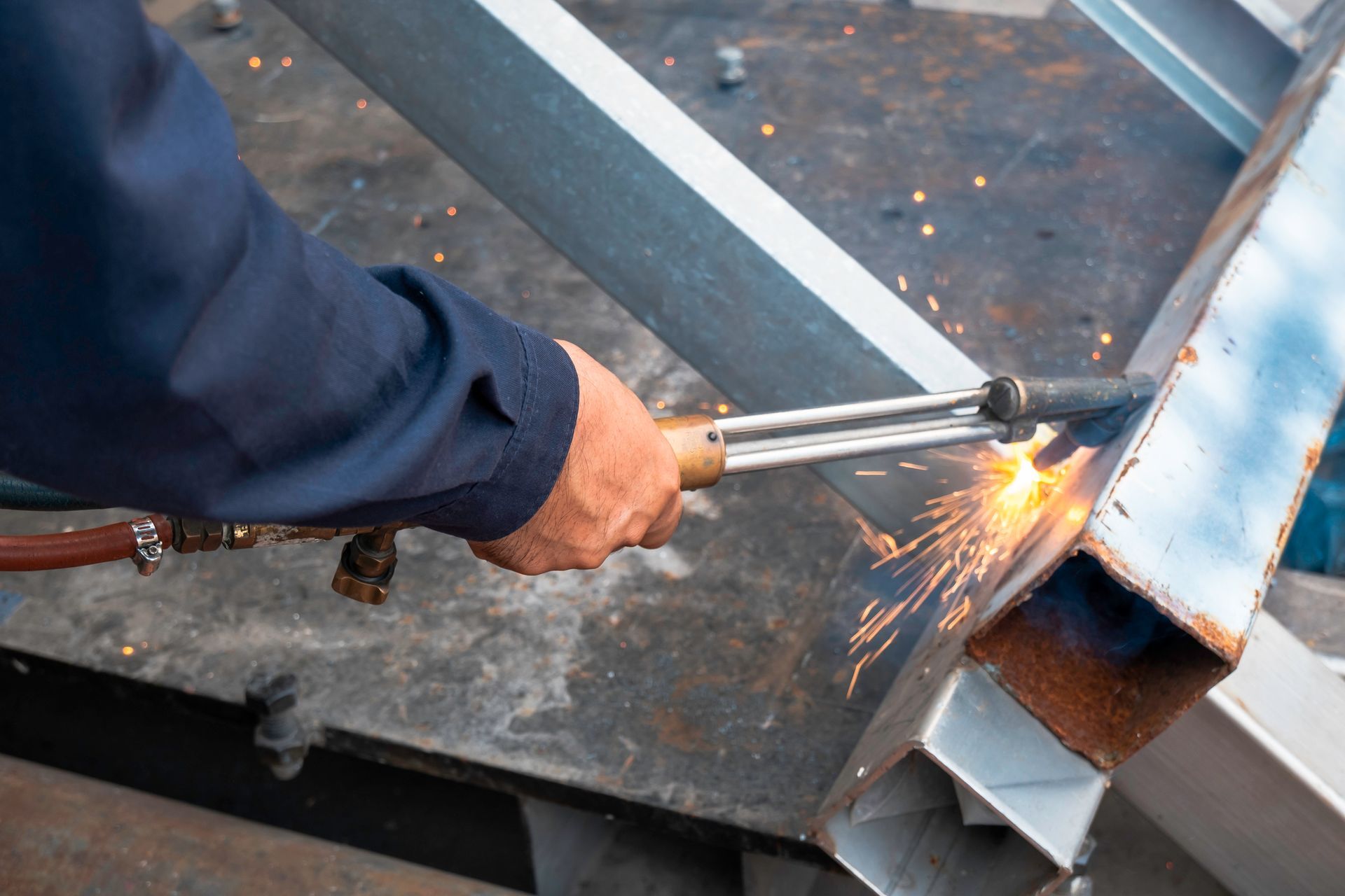 A man is cutting a piece of metal with a torch.