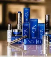 A collection of ZO Skin Health skincare products in blue packaging displayed on a reflective surface against a blurred background.