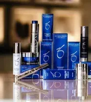 A collection of blue and silver ZO Skin Health skincare products arranged on a reflective surface.