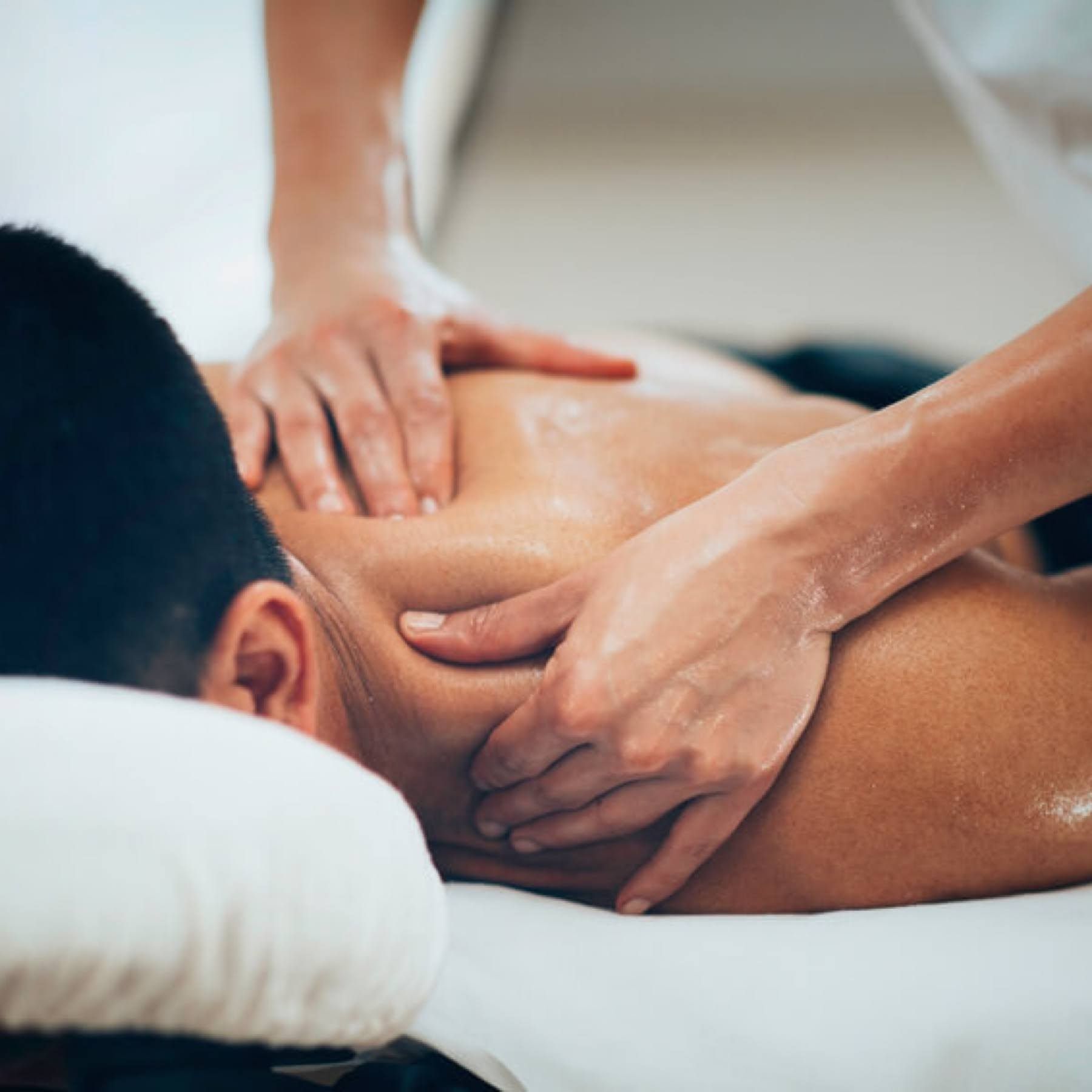 A person receiving a shoulder massage from a massage therapist in a spa setting.
