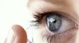 un occhio mentre si mette con l'indice una lente a contatto