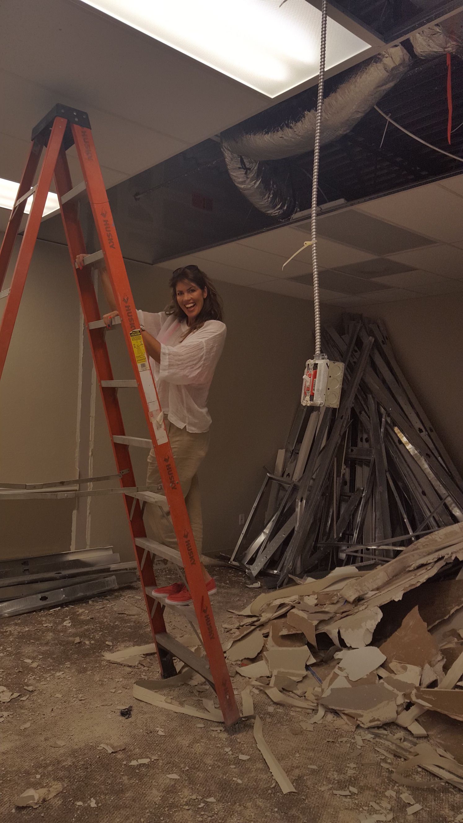 A woman is standing on a ladder in a room.