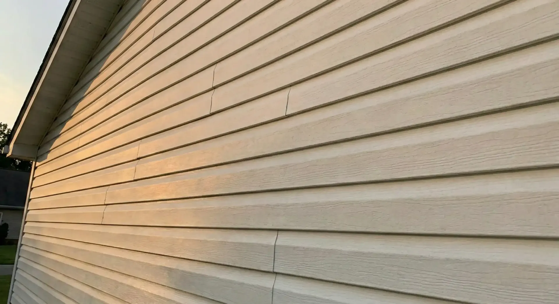 Beige vinyl siding on the side of a building, with horizontal grooves.