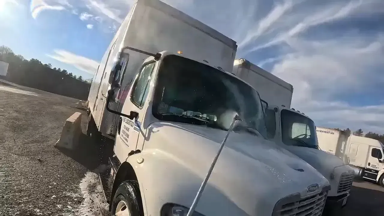 White box trucks parked outside on a sunny day.