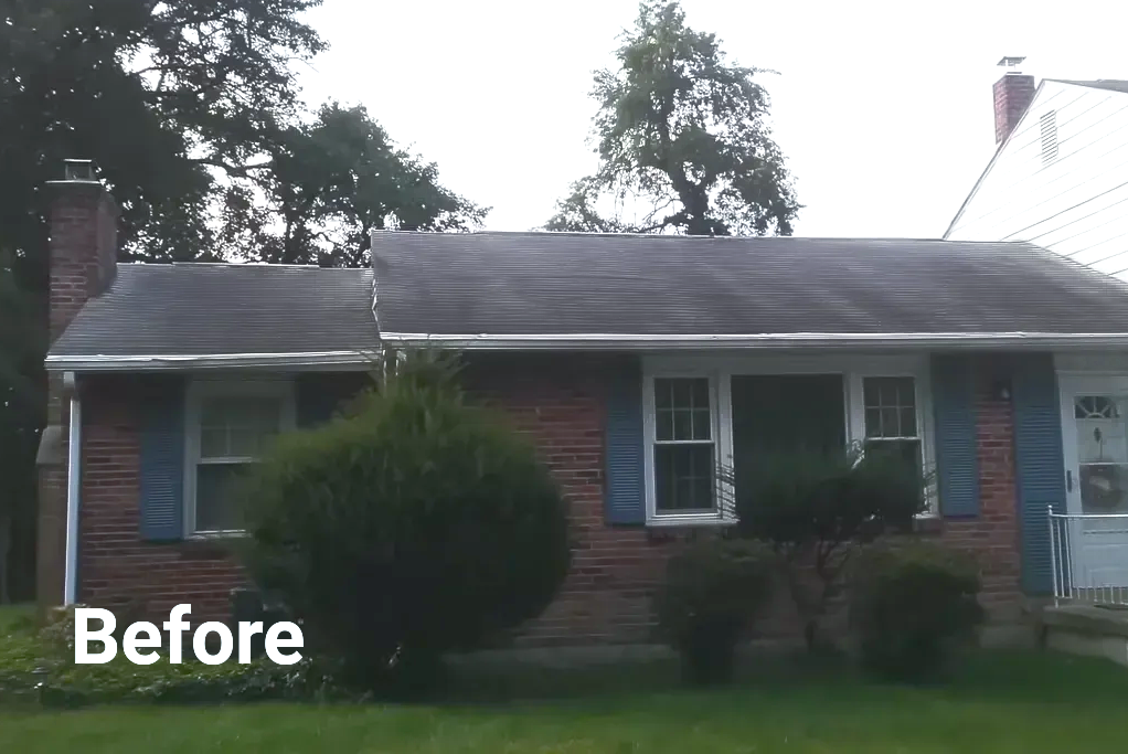 Brick house with dark roof, blue shutters, bushes, and chimney;