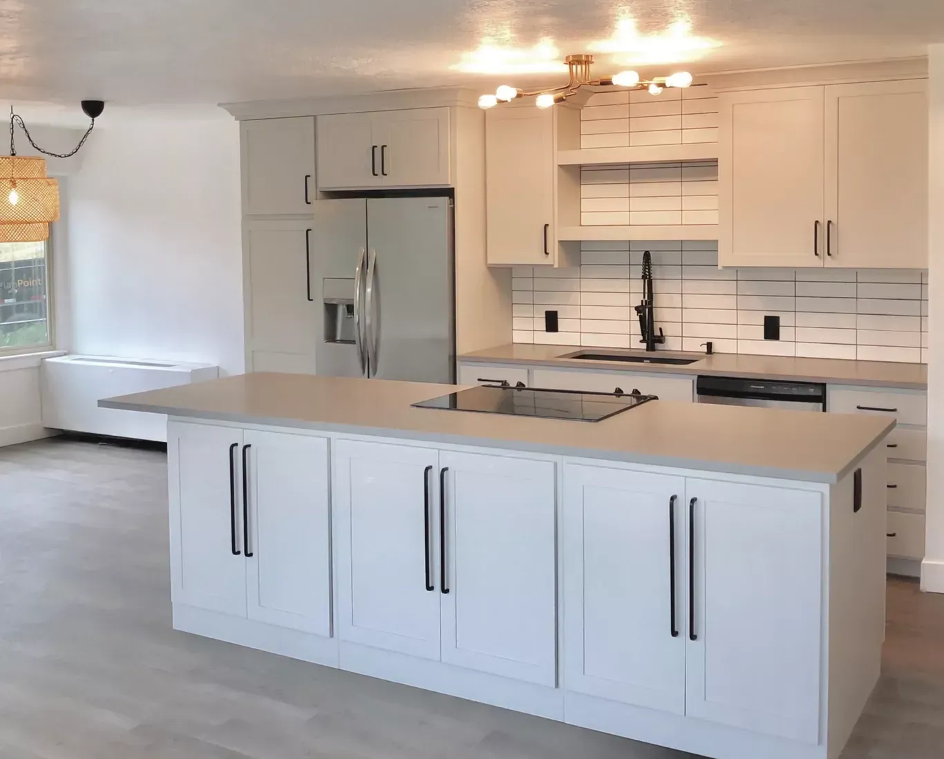 Modern white kitchen with island, stainless steel appliances, and light gray countertops.