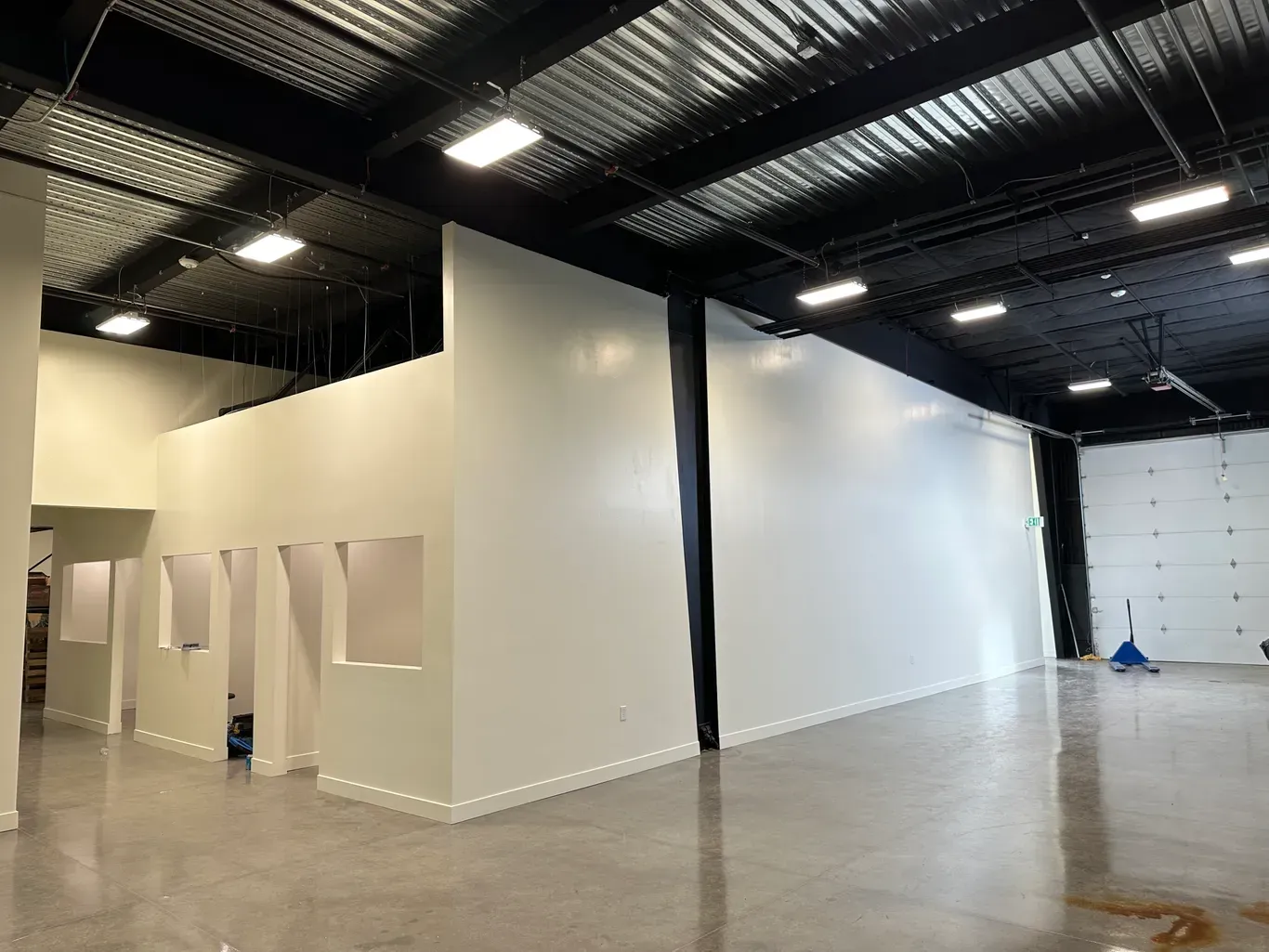 Large, empty industrial space with white walls, black ceiling, and concrete floor.