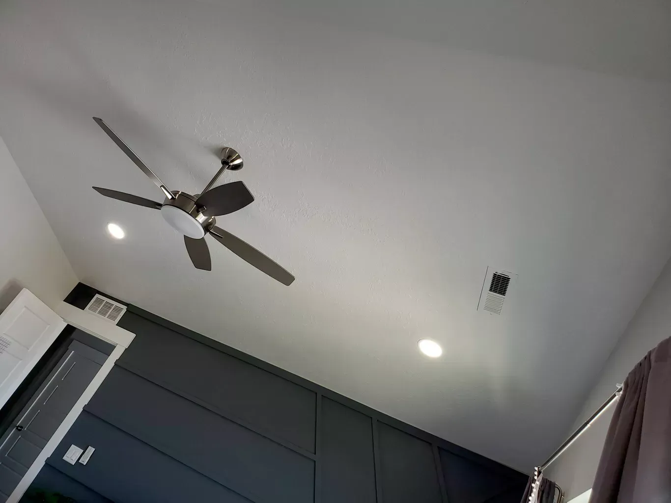 Ceiling with a fan and recessed lighting above dark cabinets. A missing outlet cover is visible.