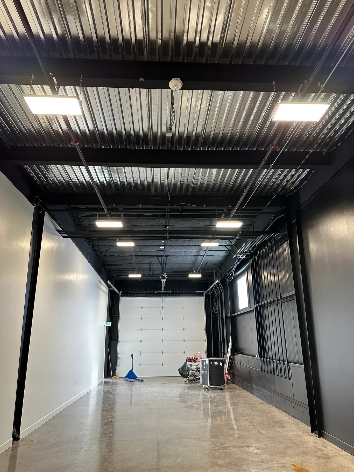 Interior of a modern building, dark walls, white walls, metal ceiling with lights, concrete floor.