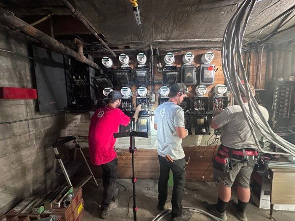 Field engineer in yellow hard hat working on electrical outlets, near blue wall.