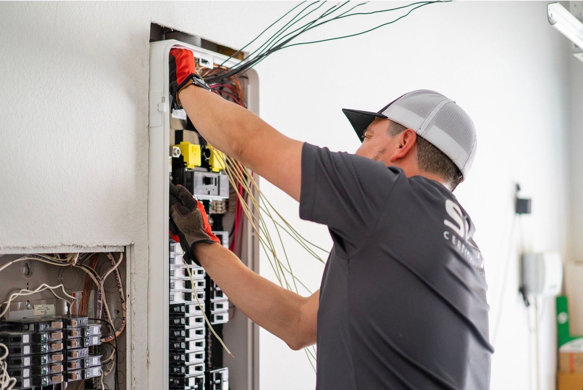 Hands of an electrician wiring a control panel with orange crimping tool.
