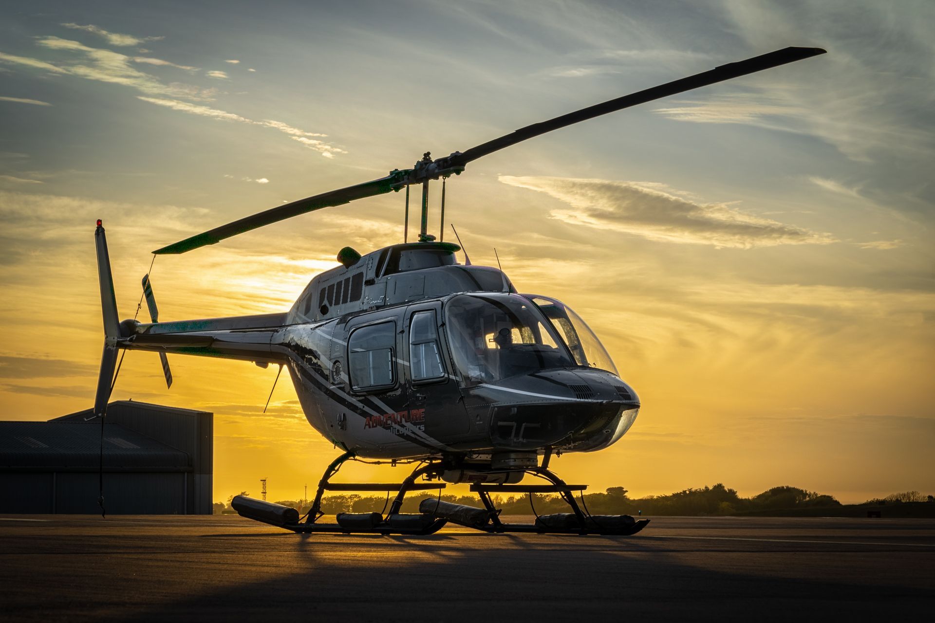 Helicopter on a runway at sunset with golden sky and long shadows