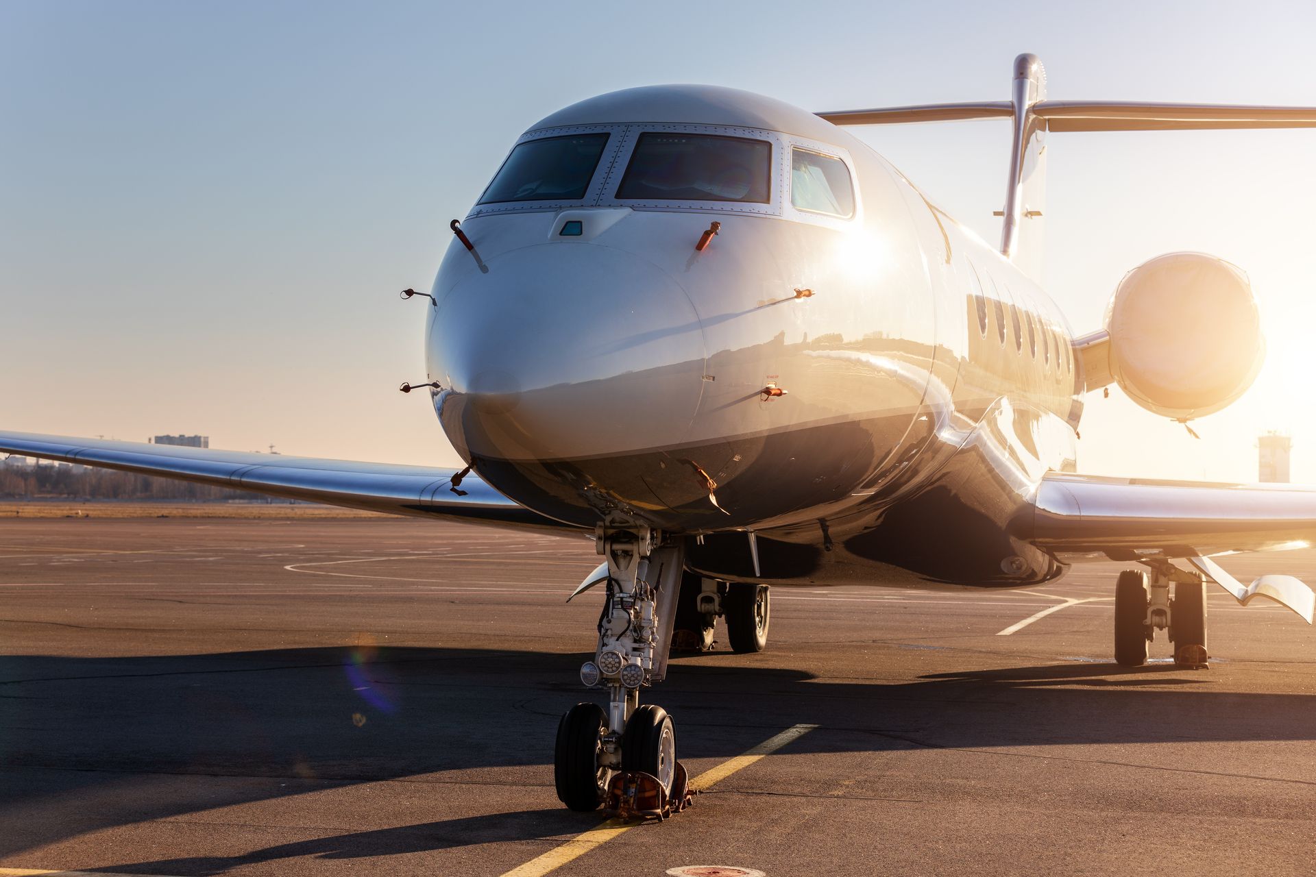 A sleek private jet parked on a sunny tarmac, illuminated by the sun.