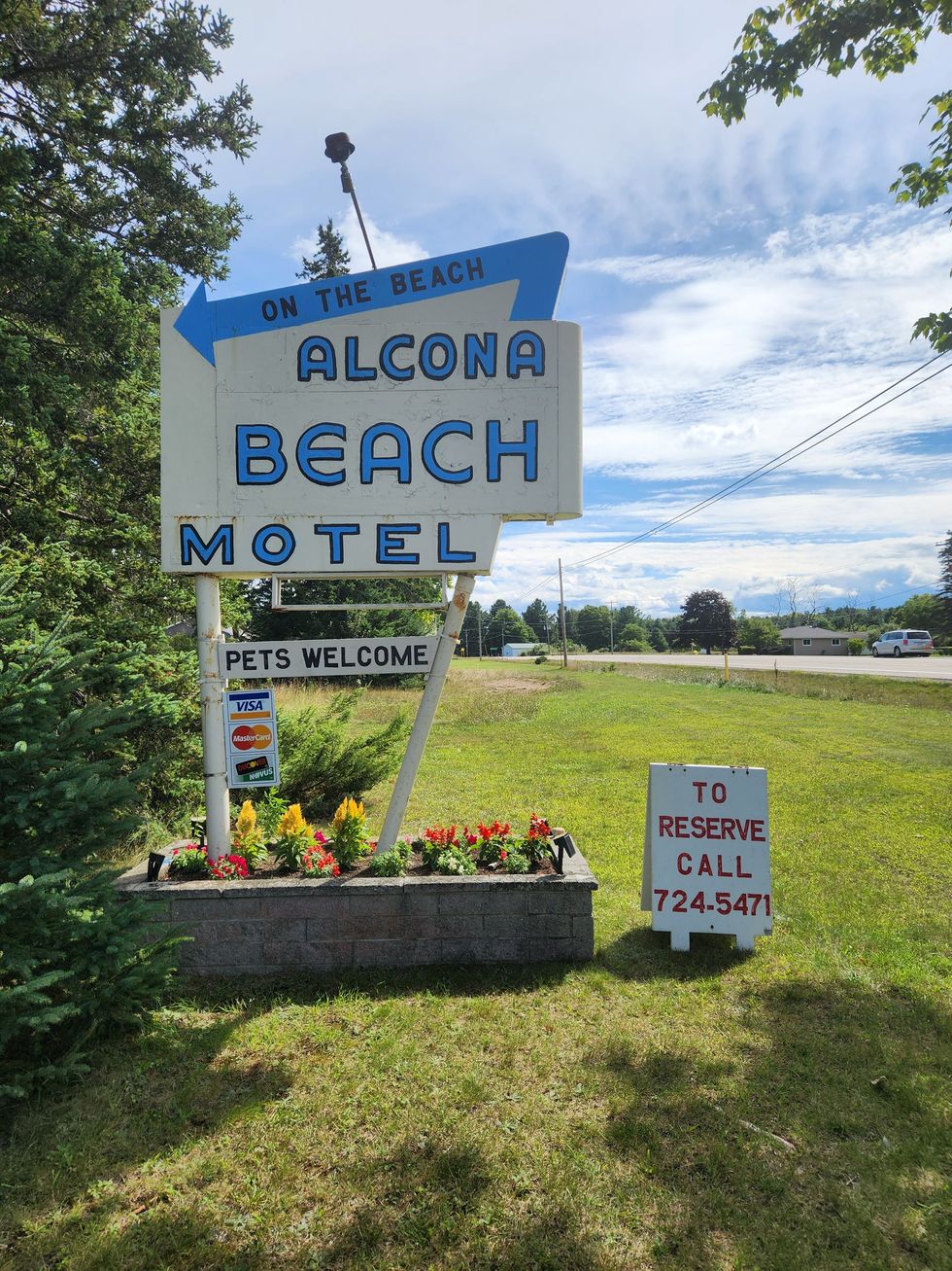 A sign that says alcona beach motel on it