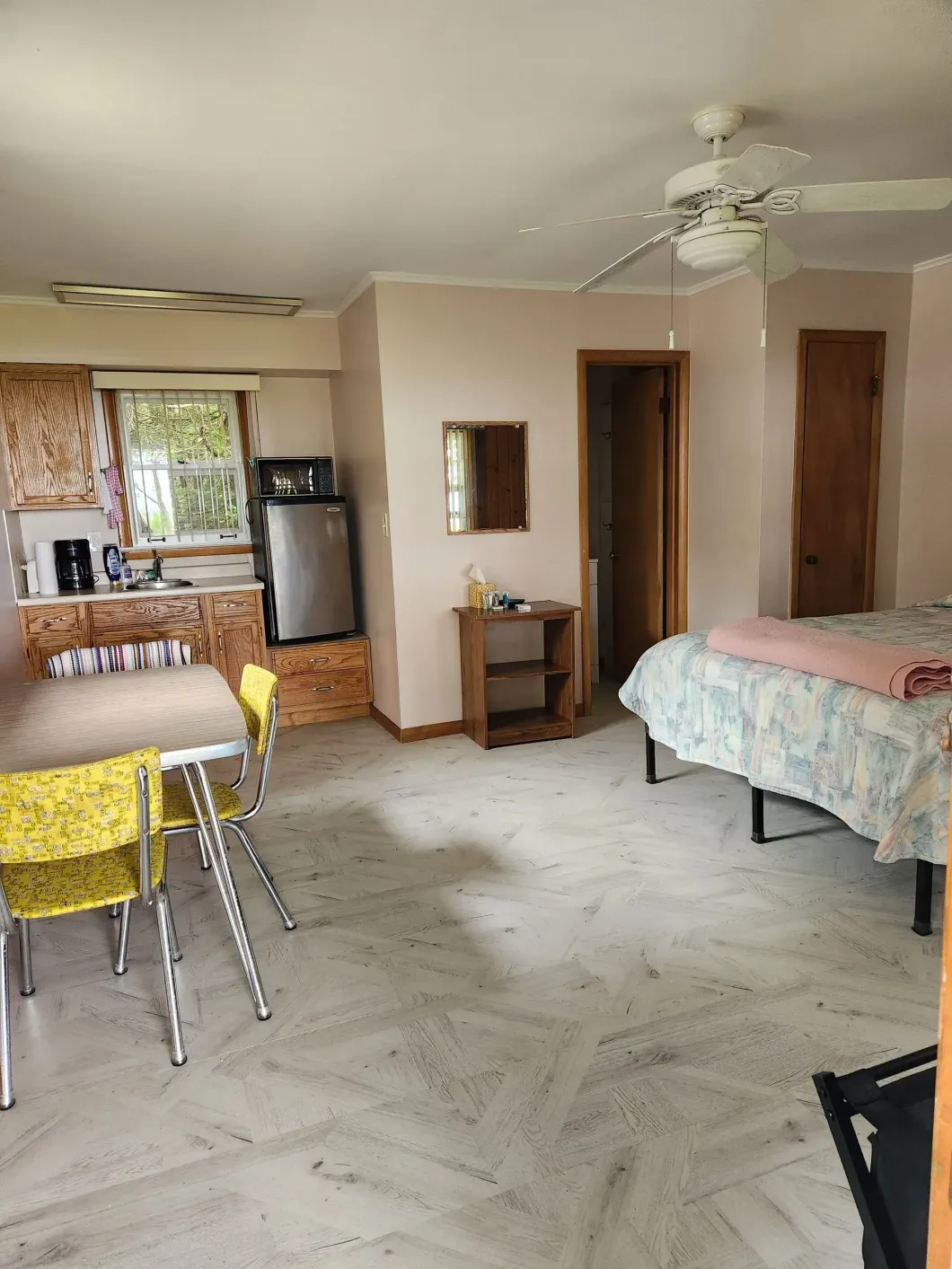 A hotel room with a bed a table and a refrigerator
