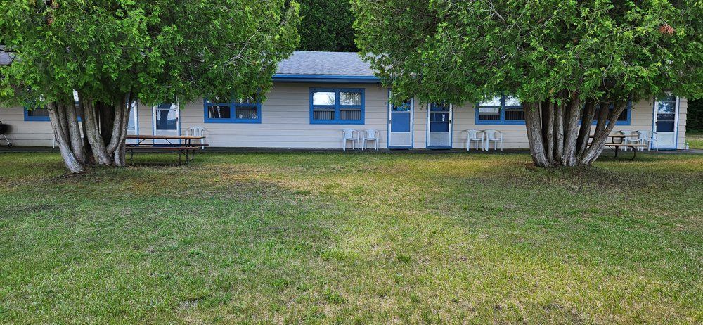 A motel with a picnic table and chairs in front of it