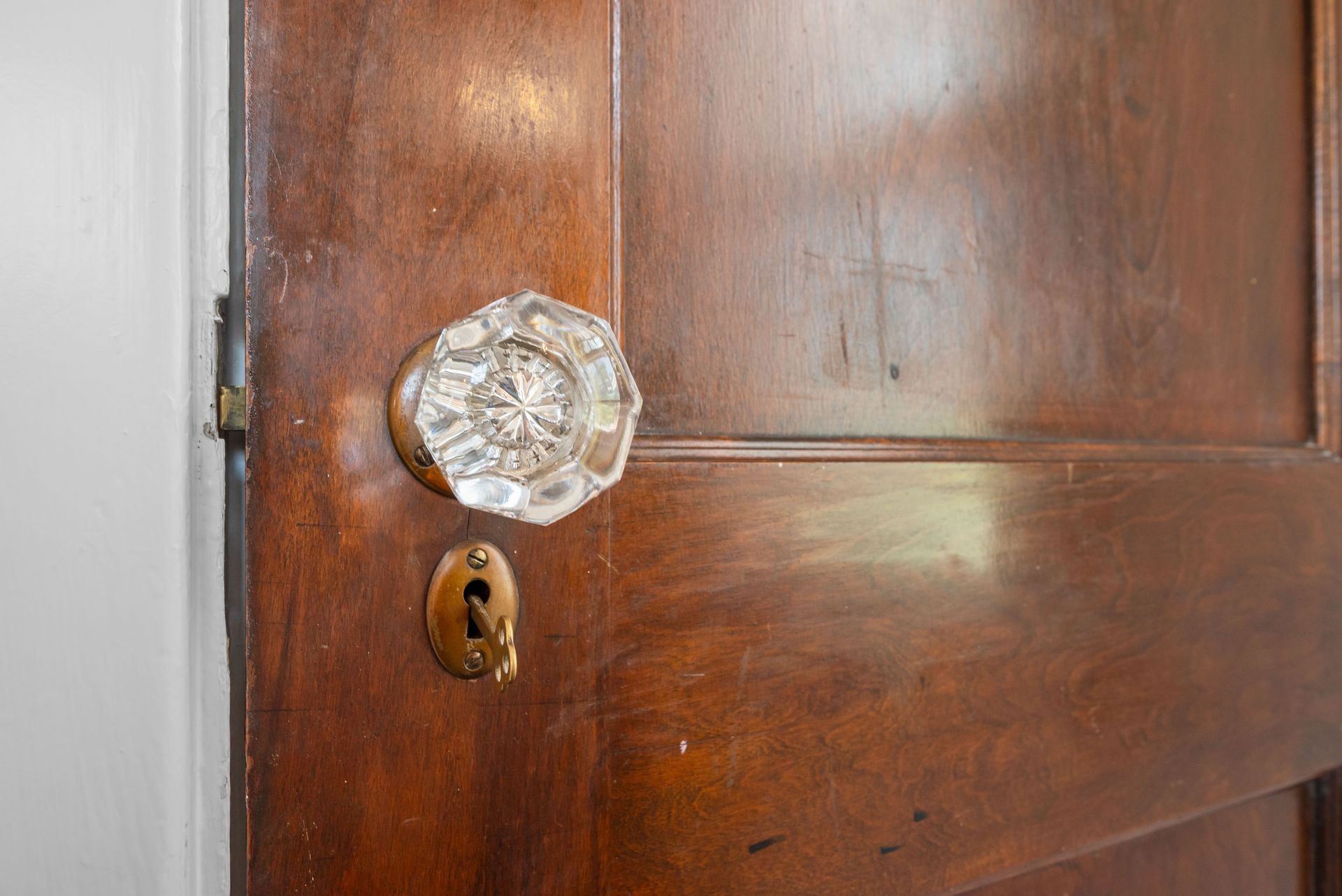 Close-up of a wooden door with a clear glass doorknob and keyhole.