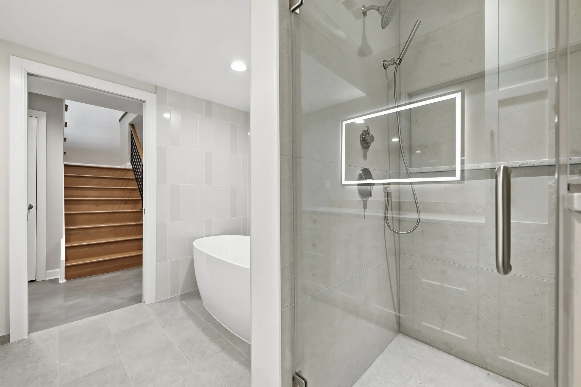 A bathroom with white tiles and a shower head - Omaha, NE - BluePrint Construction