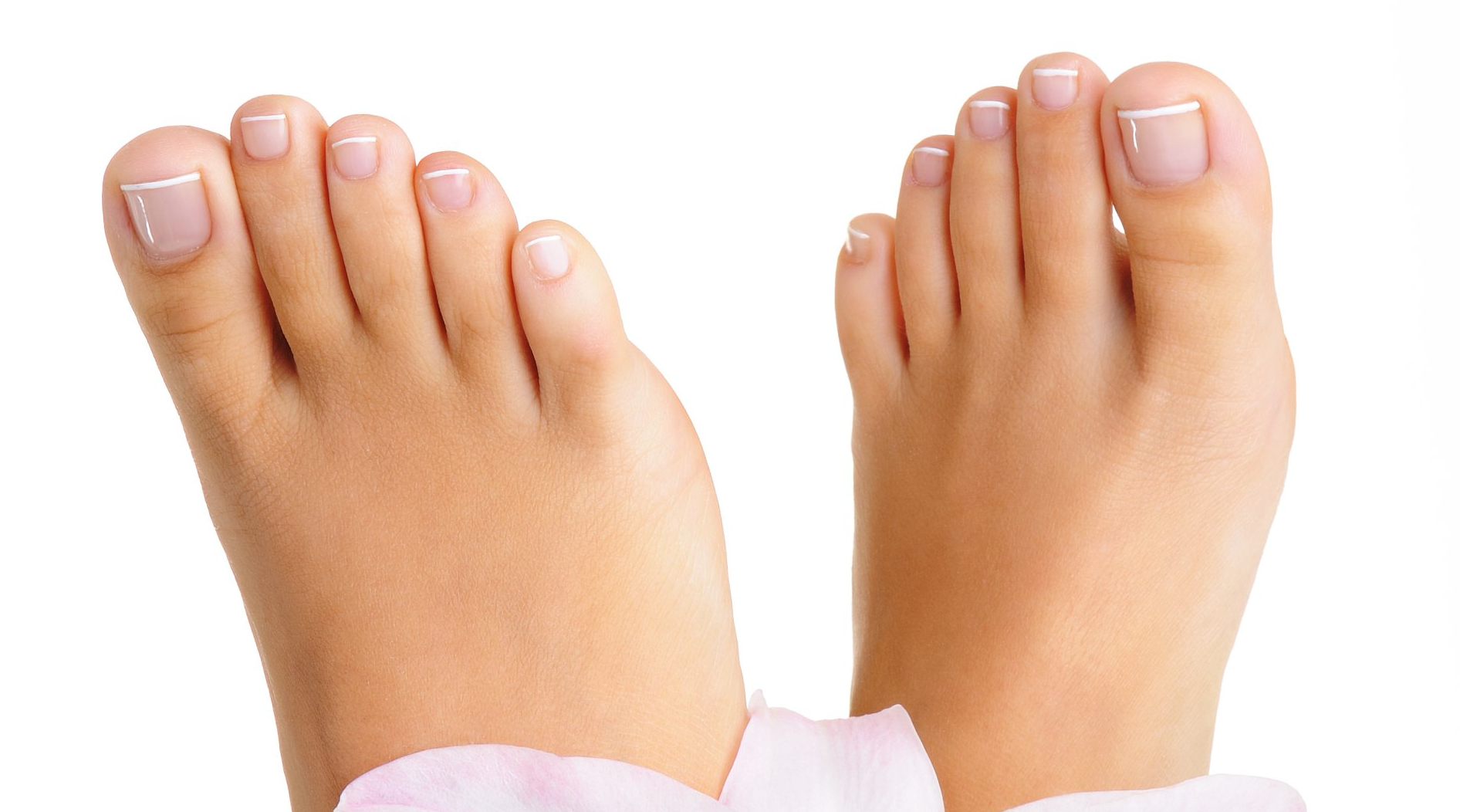 Eine Nahaufnahme der Füße einer Frau mit rosa Blütenblättern auf weißem Hintergrund.