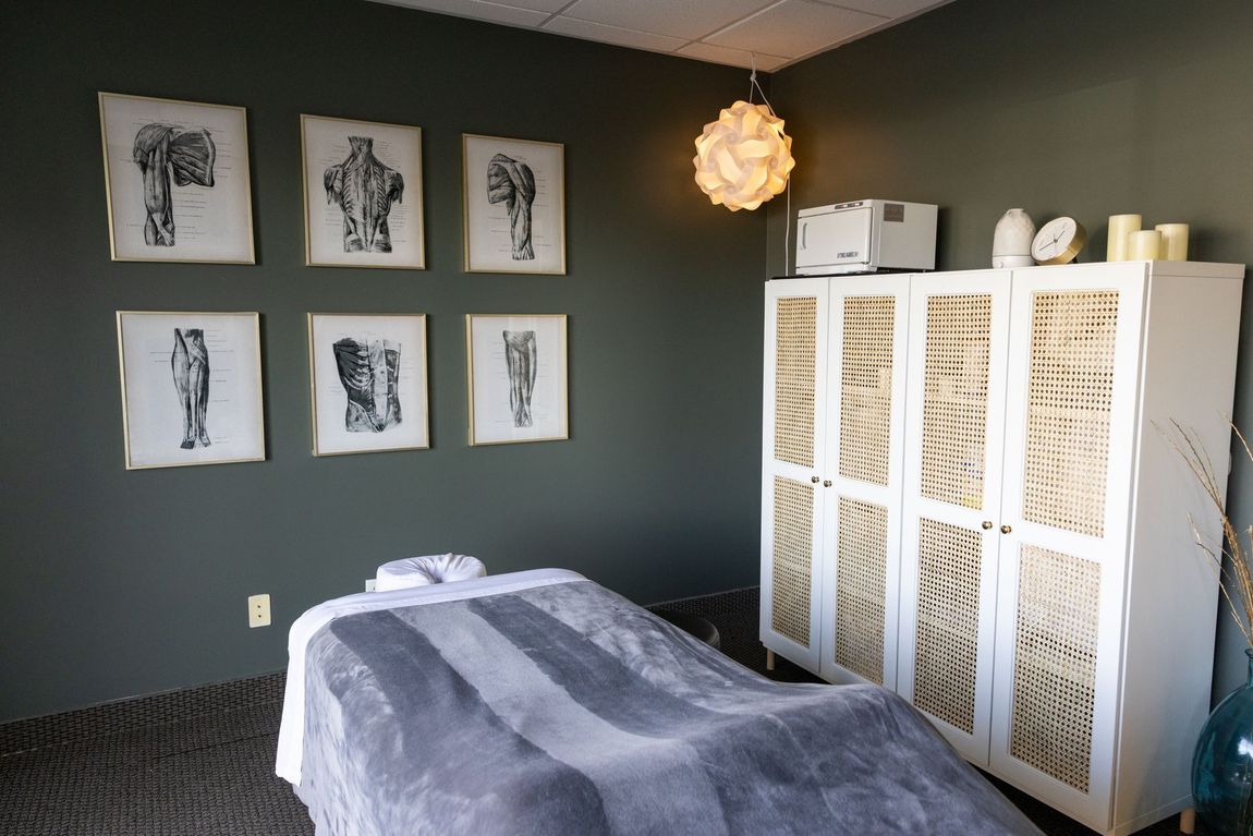 A massage table in a room with a chair and a mirror.