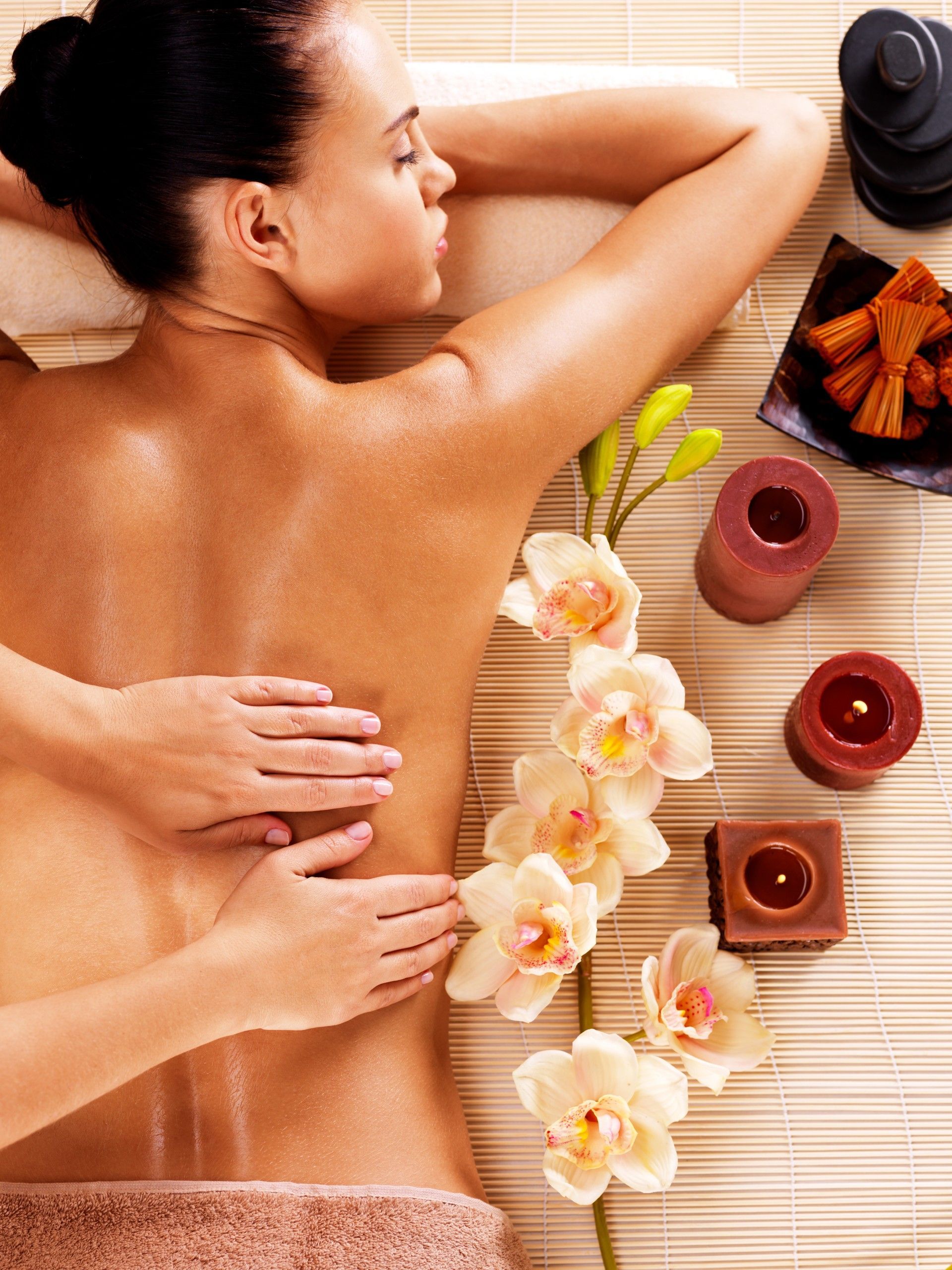 A woman is getting a massage in a spa surrounded by flowers and candles.