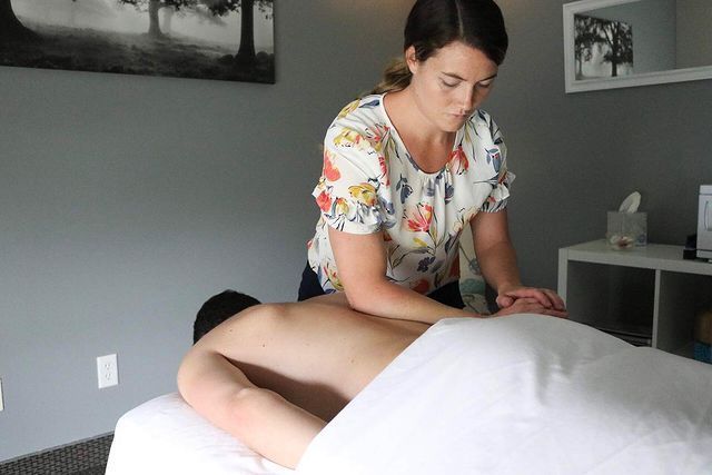 A woman is giving a man a massage on a table.