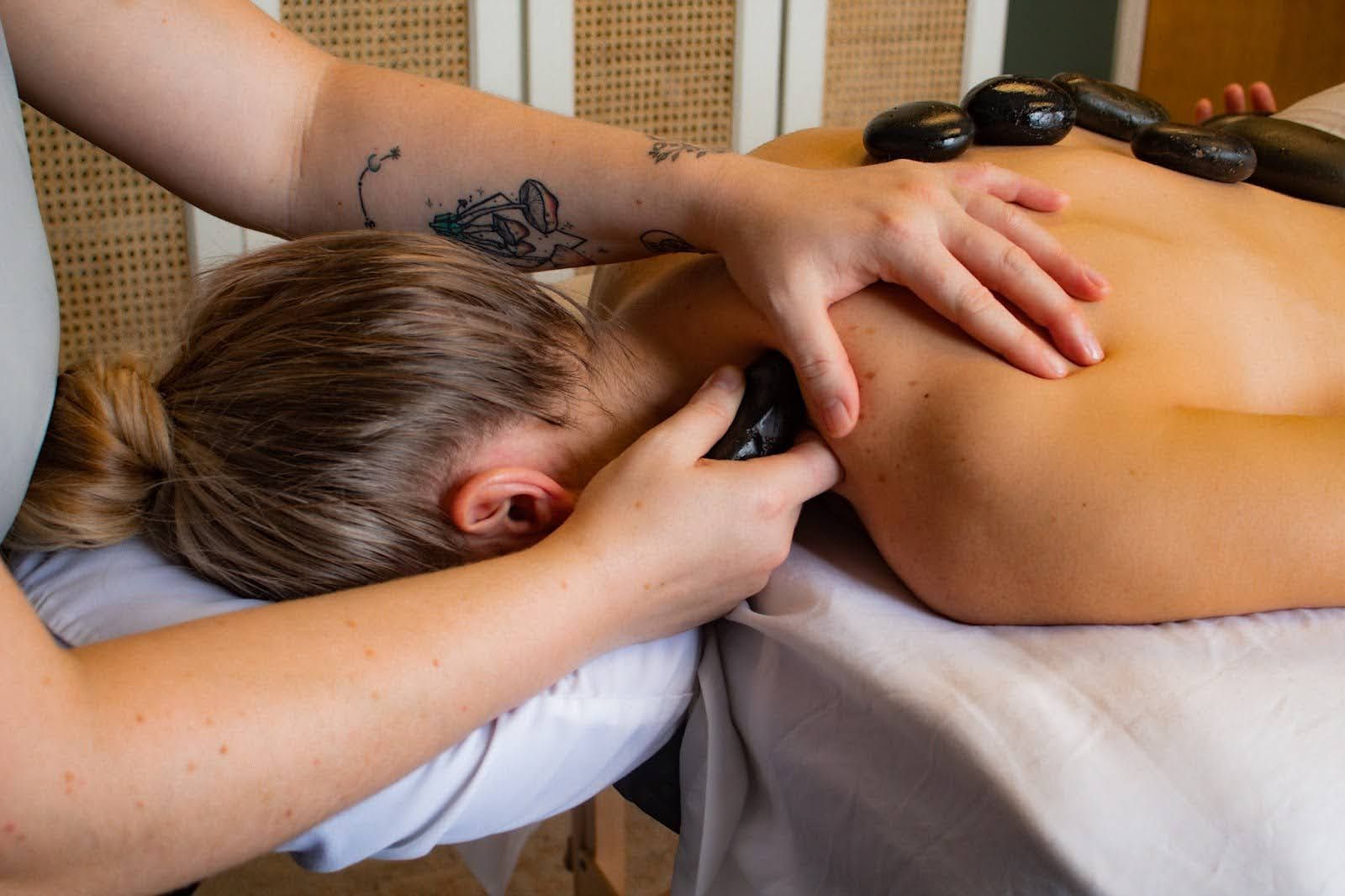 A woman is getting a hot stone massage on her back.