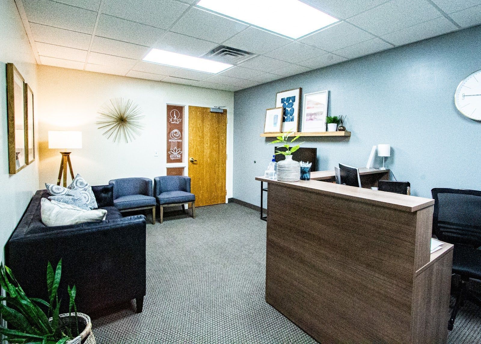 A waiting room with a couch , chairs , and a desk.