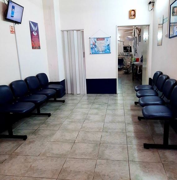 Una sala de espera con sillas azules y un televisor en la pared