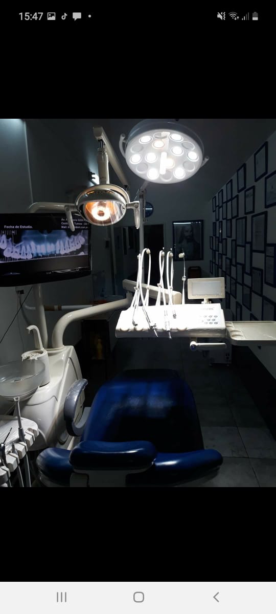 Un consultorio dental con sillón dental y lámpara dental.