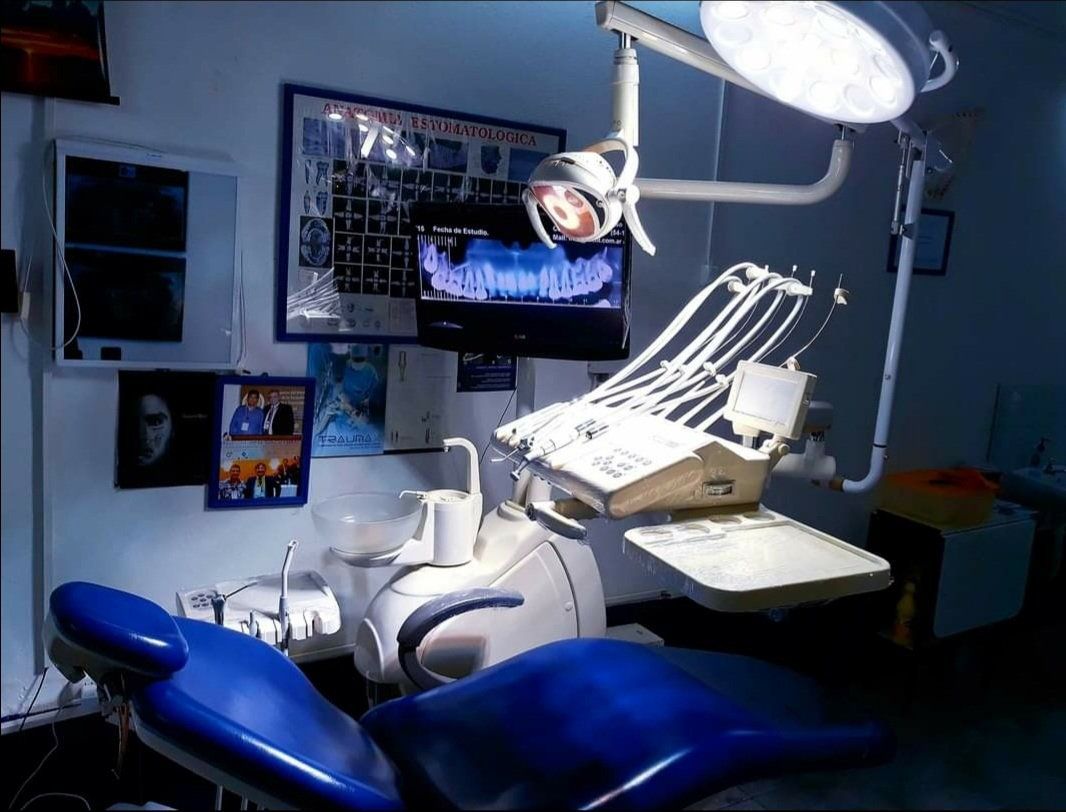 Un consultorio dental con una silla azul y un monitor