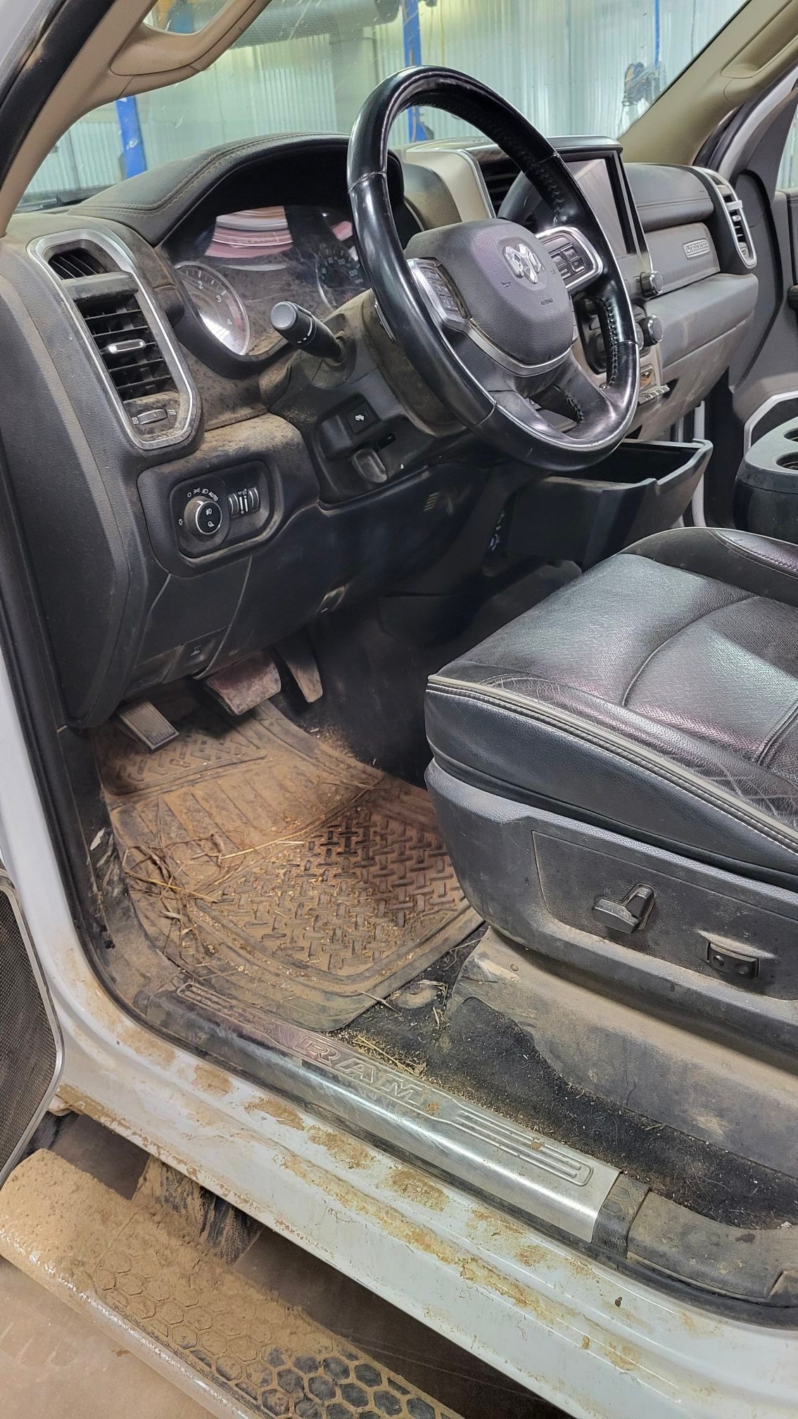 Dirty interior of a Ram truck, showing the driver's seat, dashboard, and floor covered in dirt.