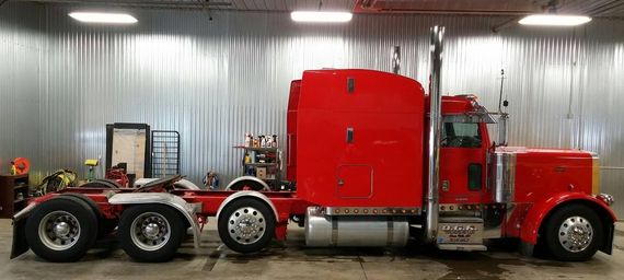 A red semi truck is parked in a garage.