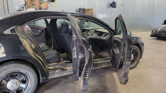 A black car is sitting in a garage with its doors open.