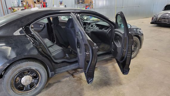A black car with its doors open is parked in a garage.