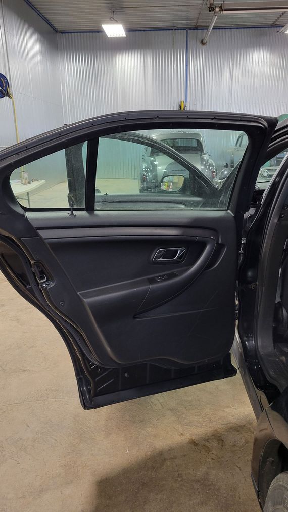 The back door of a black car is open in a garage.