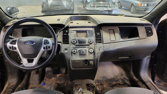 The interior of a dirty car with a steering wheel and dashboard.