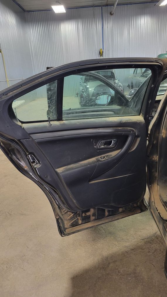 The back door of a black car is open in a garage.