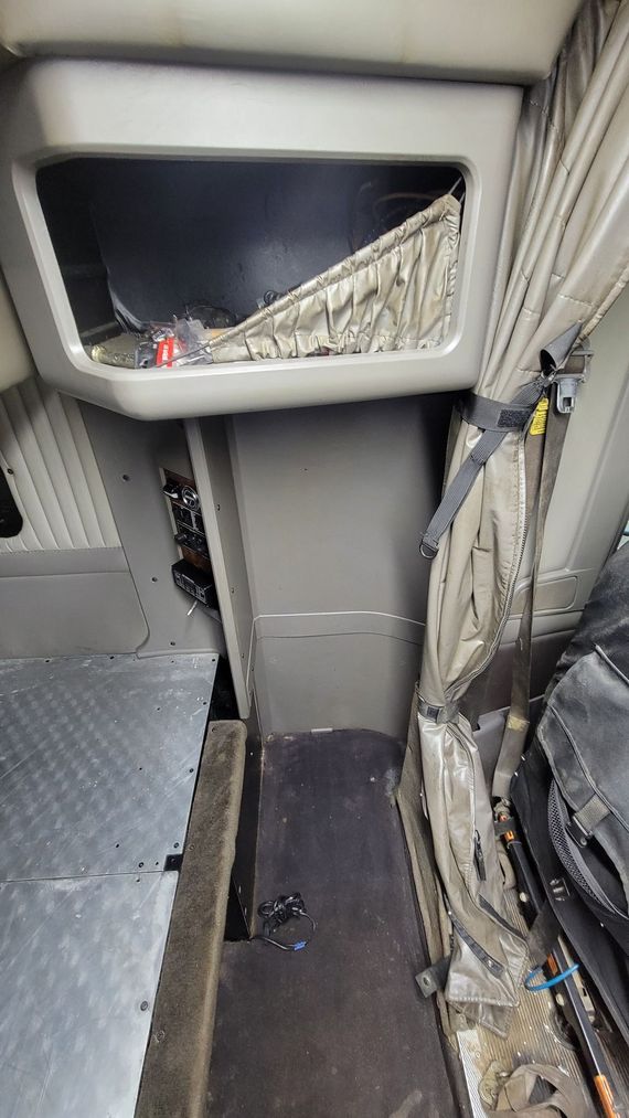 The inside of a semi truck with a shelf on the ceiling.