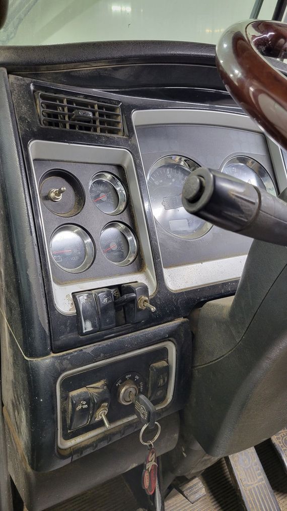 A close up of the dashboard of a truck with a steering wheel.