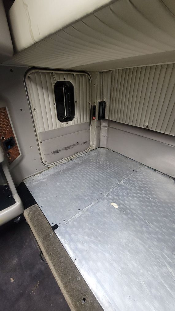 The inside of a truck with a bed and a window.