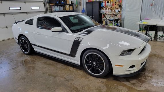 A white ford mustang is parked in a garage.