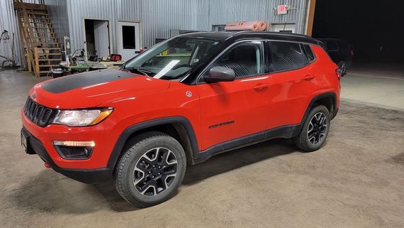 A red jeep compass is parked in a garage.