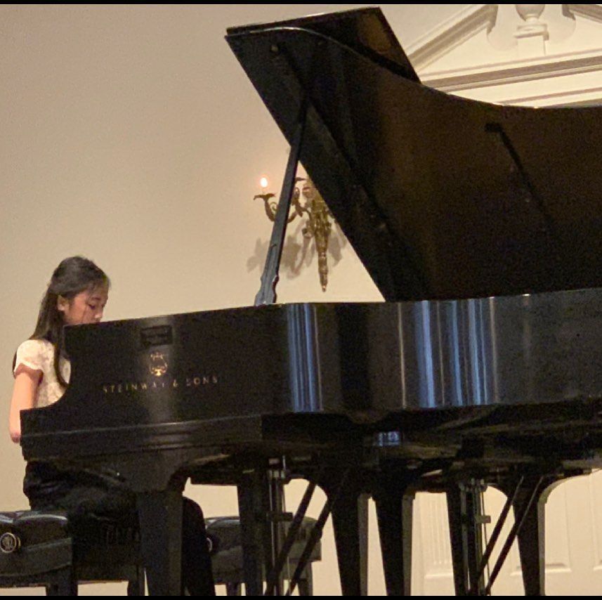 A young girl is playing a steinway & sons piano