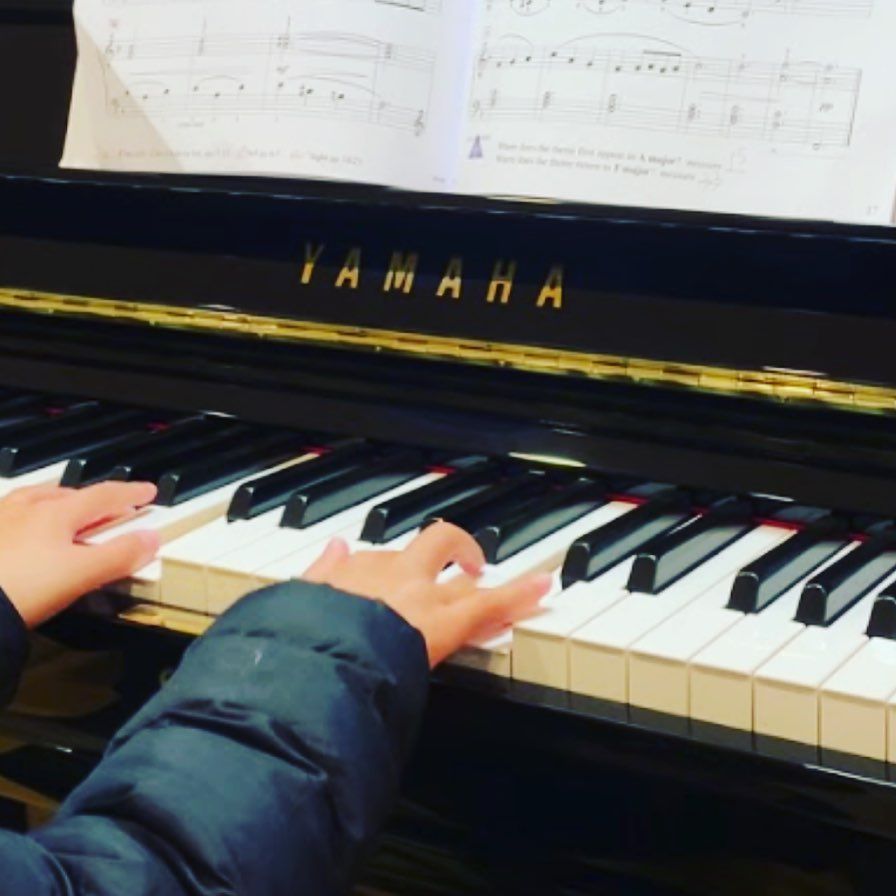 A person is playing a yamaha grand piano