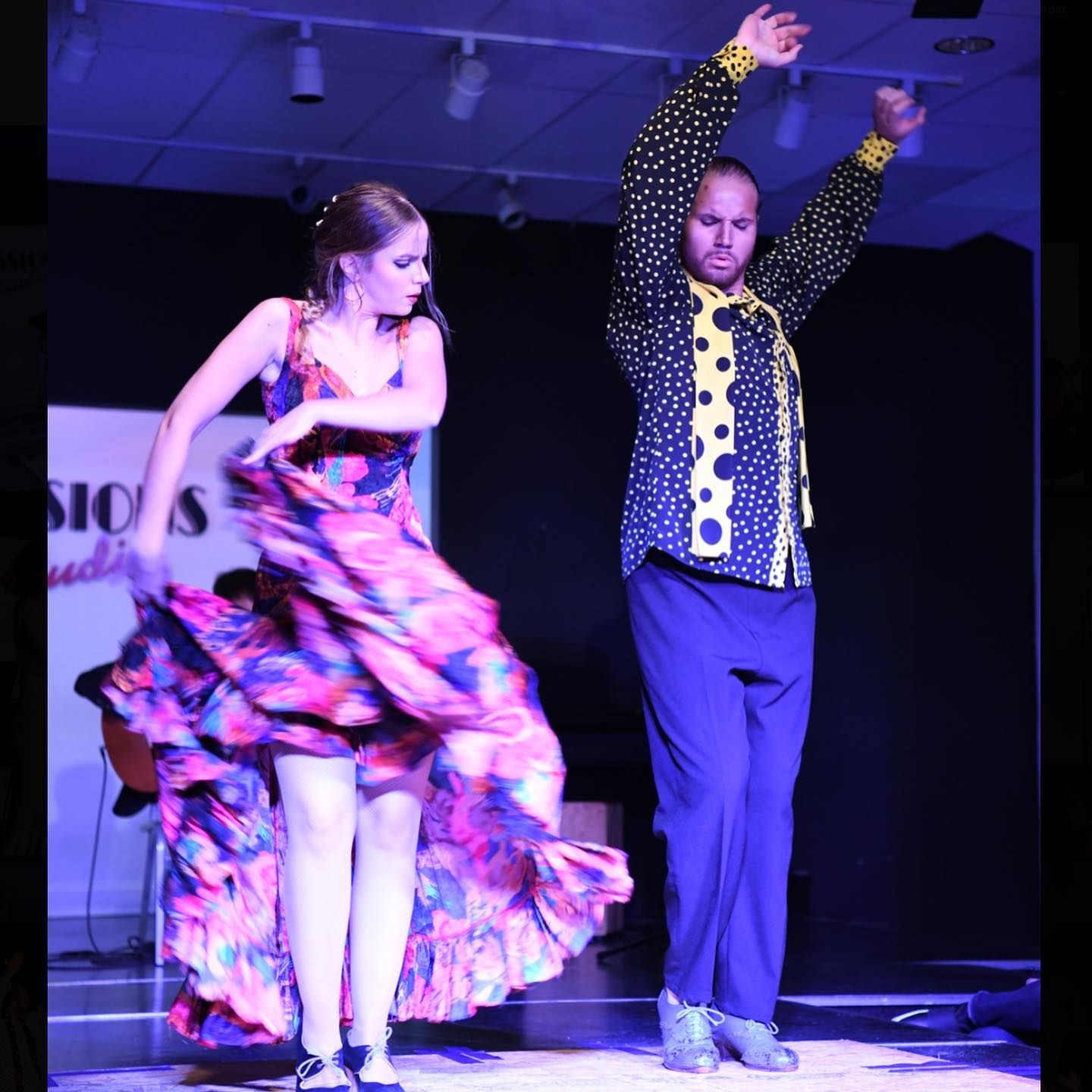 A man and a woman are dancing in front of a sign that says sios