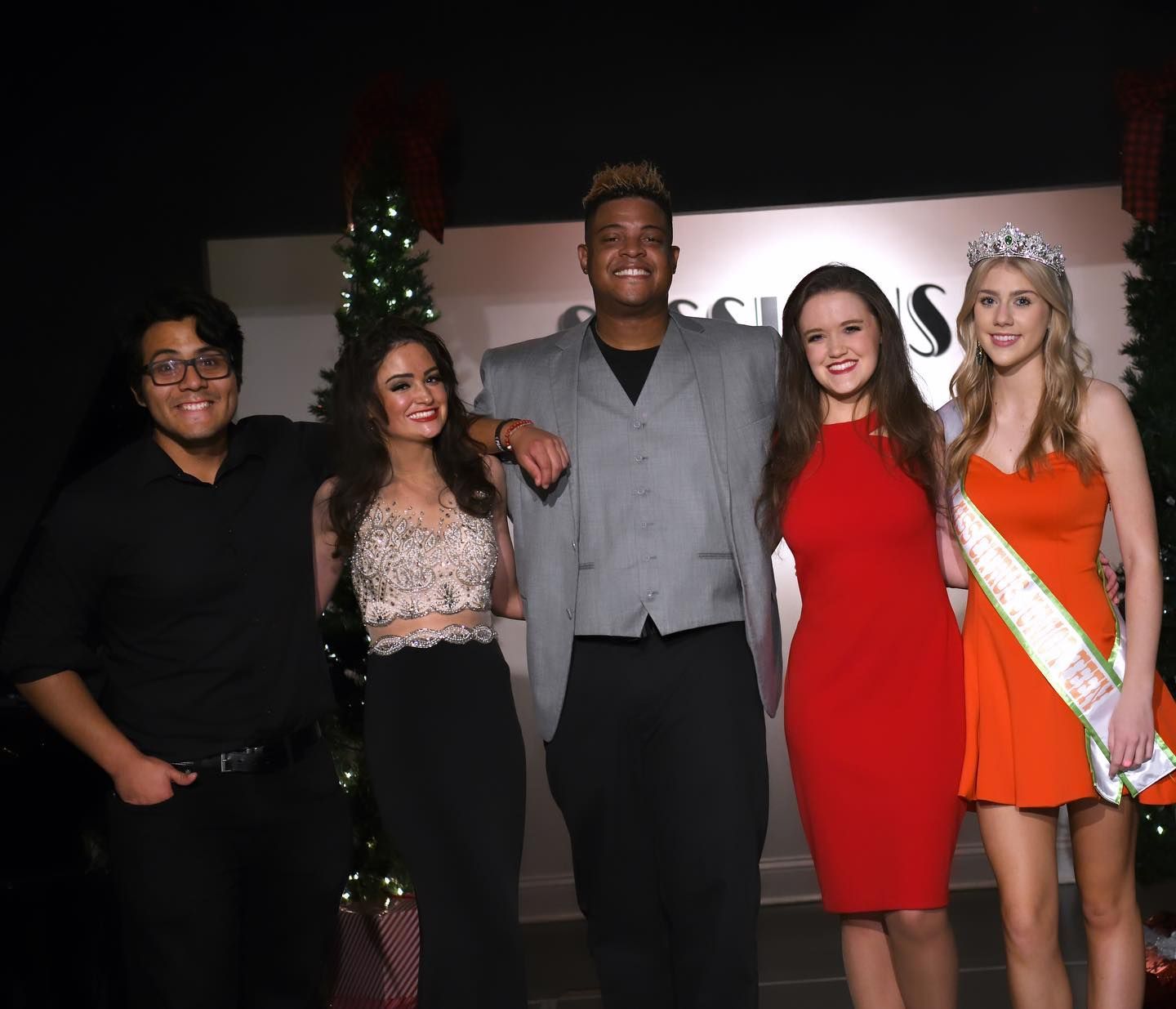 A group of people posing for a picture with the word s on the wall behind them