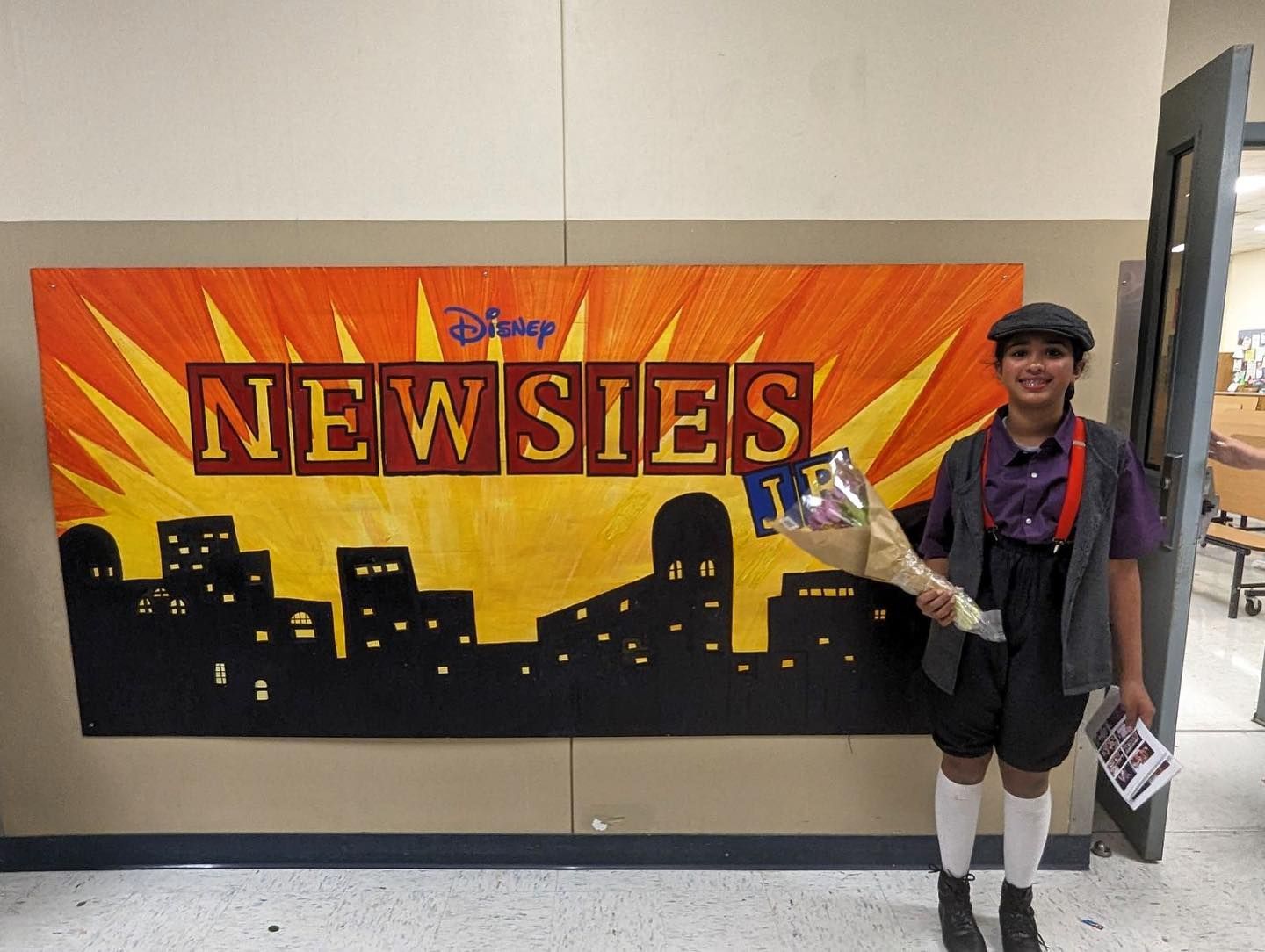 A person standing in front of a sign that says newsies